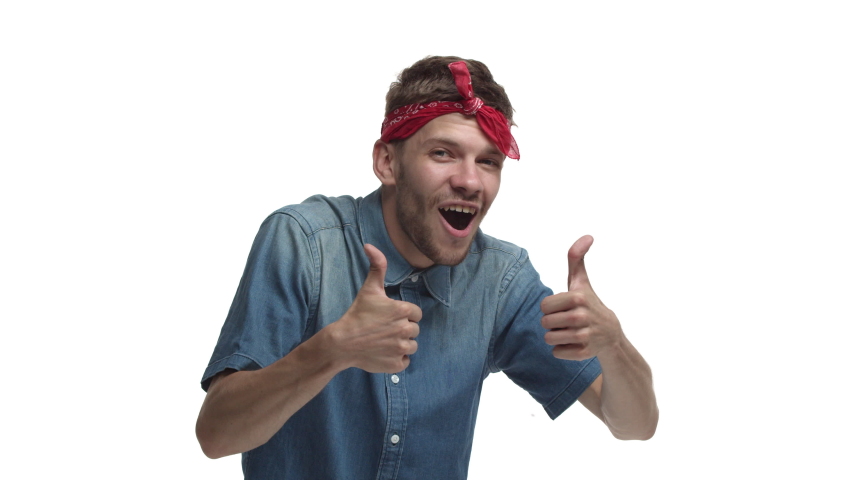 Cheerful handsome man with red headband over forehead, showing thumbs-up in approval, praise you and making compliment, standing pleased over white background
