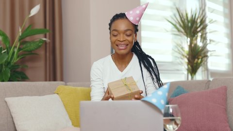 Portrait young african american woman hold gift speaking on video call use laptop. Birthday girl staying home for self-isolation. Slow motion