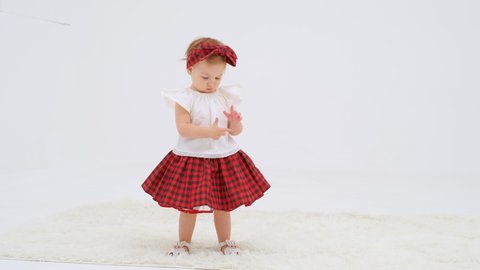 Little girl in plaid headband and skirt is dancing. Close up slow motion