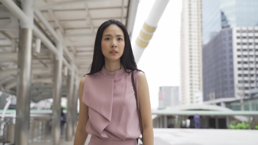 Young Asian businesswoman looking at watch and speed walking near office building. Attractive Asia business girl in rush and hurry for meeting. Chinese Korean pretty lady late for work - 4K Footage | Shutterstock HD Video #1061645347