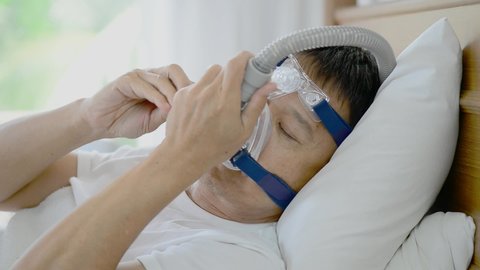 Healthy senior man wearing ventilator mask and adjusting to fit his face ,healthcare concept.
Obstructive sleep apnea therapy,hd video.