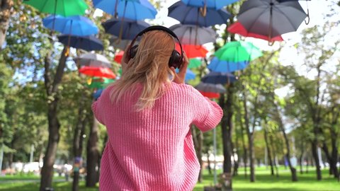 Back view, Young american teenager girl using headphones, listen to music, park, outdoor