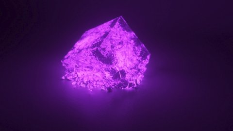 A cube of bright glowing stone shatters into thousands of small pieces in slow motion. Destruction concept