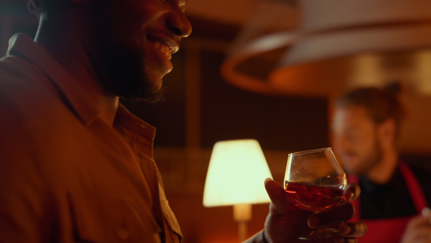 Closeup relaxed afro couple resting and having fun in restaurant. African american people drinking alcohol drinks in bar at evening. Cheerful african man and woman dancing in nightclub party. Royalty-Free Stock Footage #1061653273