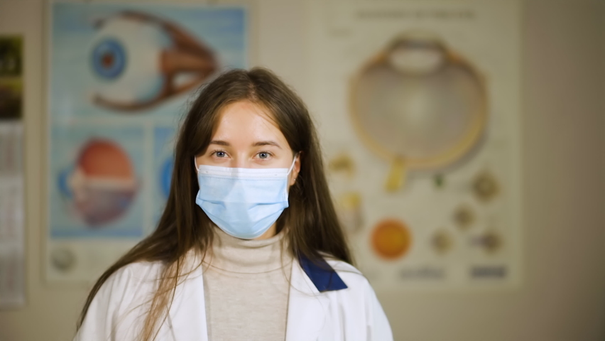 Happy young doctor in medical face mask looks at you | Shutterstock HD Video #1061653660