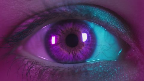 Close up shot of eye opening with pink iris. Healthy eyesight concept. Female pink eye in neon light. Young sexy girl in a nightclub. Macro look of the human eye. Pink-blue-green color, euphoria.