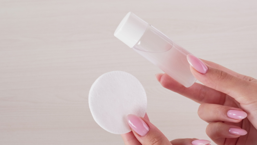 Skincare product. Face cleansing. Hygiene wellness. Female hands showing clear mockup bottle with tonic cotton pad on light blur wooden texture empty space background loop. | Shutterstock HD Video #1061655484