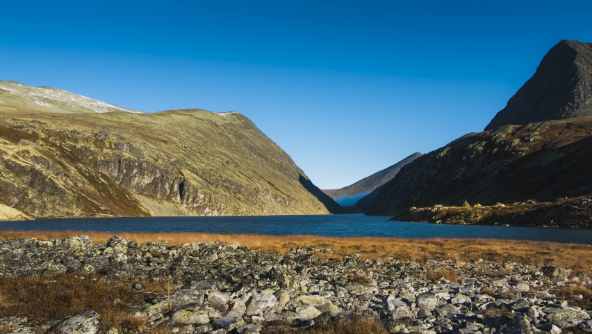 Small lake in valley on top of mountain with clouds