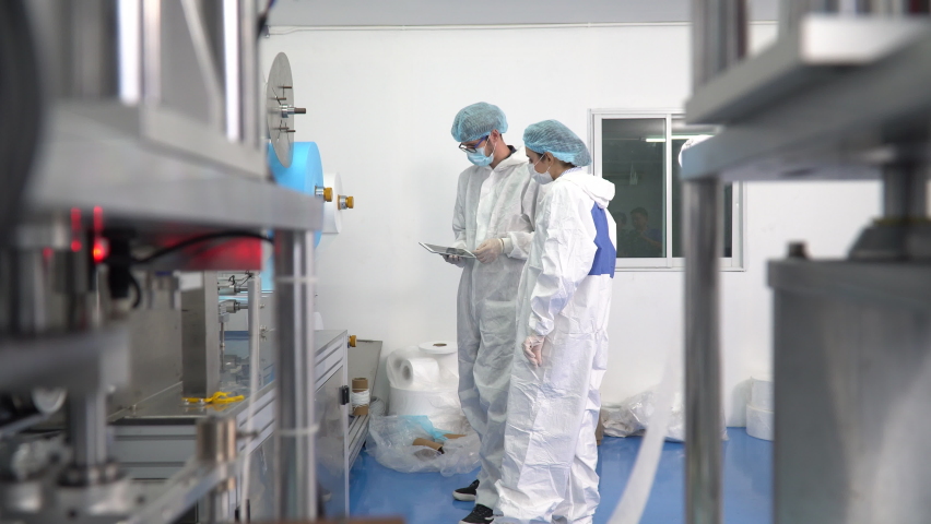 Group of engineer worker wearing ppe suite, face protective mask, glove useing digital tablet analyze  operation and check quality, Maintenance of mask manufacturing machine at lab in industry factory Royalty-Free Stock Footage #1061659078