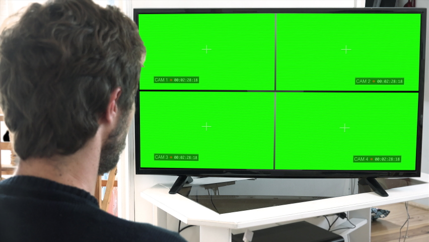 Isolated Man Watch CCTV Cameras Chroma Key Monitor. Headshot of a man watching recorded cameras on a split screen monitor. Green screen background