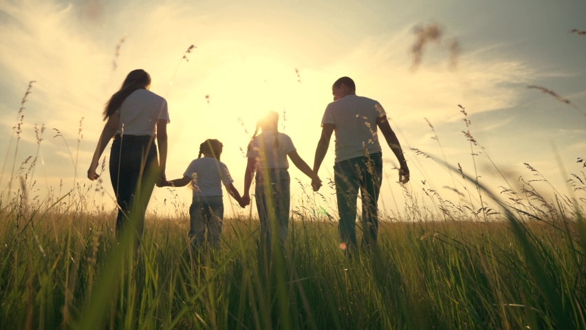 Happy family in park at sunset. Parents and children hiking in field in park. Silhouette of a happy family in park at sunset. Children are dreaming in green field. Silhouette of happy family hiking Royalty-Free Stock Footage #1061664205