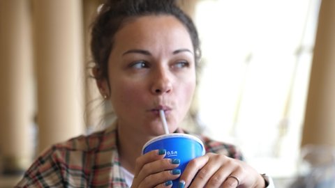 Young Caucasian woman enjoying a drink with the straw. Drinking cola or soda pop with a straw. Close up portrait shot.