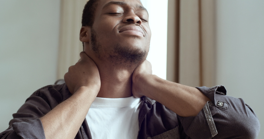 Portrait of young African American business man student freelancer sitting in office home table feeling pain in neck tired expression time to take rest. Mixed race guy suffering from ache in shoulders