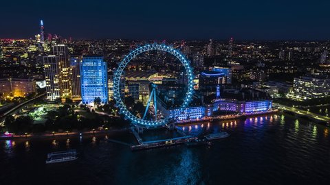 Establishing Aerial View Shot of London UK, Southbank Thames River, magnificent London Eye, Ferris Wheel, Riverside famous landmarks, United Kingdom, night evening, beautiful blue light