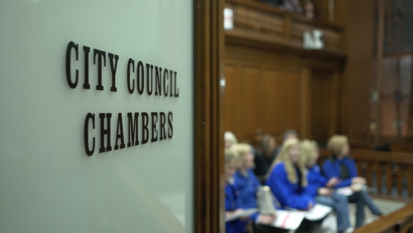 A hearing about to commence in the chambers of the city council 