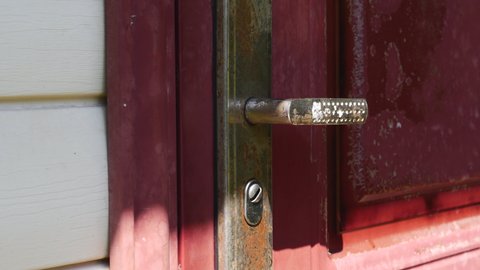 An Old Red Door With An Old Rusty Door Handle Closes Itself.