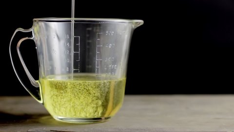 Pouring vegetable oil in a measuring glass cup.