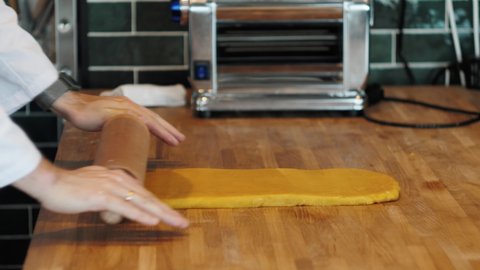 Chef making spaghetti noodles and lasagne dough with pasta machine on kitchen table with some ingredients around. Traditional italian food, high cuisine restaurant