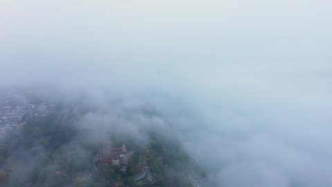 Aerial ascent into the fog with a hint of the Cloisters and the George Washington Bridge in Upper Manhattan New York City