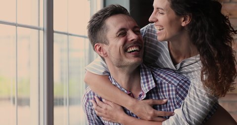 Close up portrait wife piggyback beloved husband couple smile look at camera laughing feels happy. Dating, romantic relations, family celebrate relocation to new home, move day at first house concept