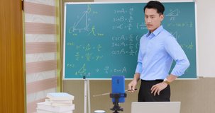 asian senior high school male teacher teach math online through mobile phone in classroom