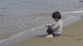 4K Video 3 years old asian kid play sand on the beach. Background for family life and education. holiday with children.