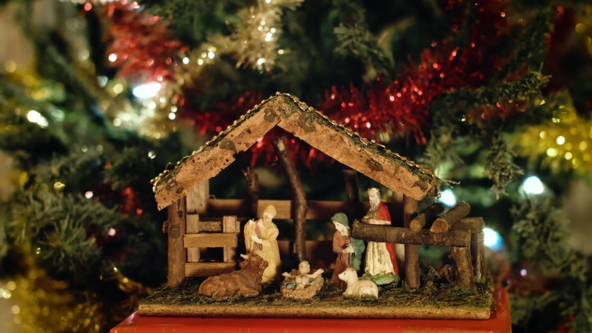 Woman puts miniature figurines of Mary in a christmas crib next to a christmas tree. Beautiful nativity scene and christmas decorations - close view | Shutterstock HD Video #1061687905