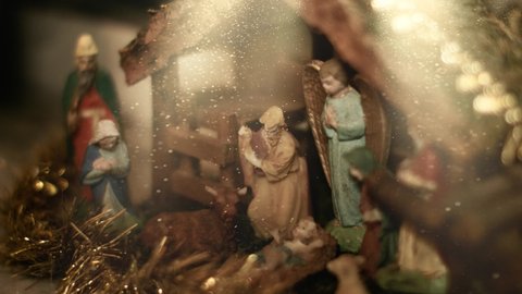 Close up view of light going on baby Jesus in a Christmas crib with snow. Beautiful nativity scene and Christmas decorations