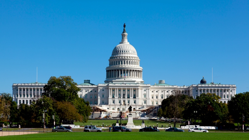 Time lapse footage of the US Capitol building in Washington DC as seen from national mall This iconic place holds senate and congress. It is a windy autumn day and clear sky. Traffic flows in street.
