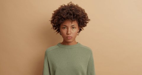 Irritated angry wife listens to husbands explanations crosses arms over body and looks with annoyed expression at camera dressed in casual jumper isolated over brown background. Negative feelings