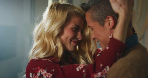 Cinematic shot of young carefree happy smiling homosexual female gay and transgender man couple in love is enjoying time together and having fun to dance together while listening to the music at home