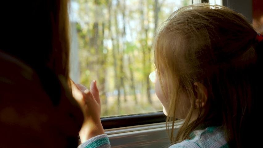 Cute little child girl smiles and looks out window of train in carriage during journey. Yellow trees and leaves background. Freedom concept, enjoy autumnal nature Royalty-Free Stock Footage #1061699095