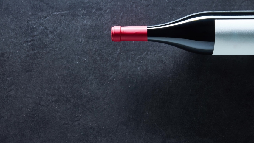 Wine corks shaped Christmas tree on black background with a bottle of red wine. Stop motion, timelapse. Copy space.