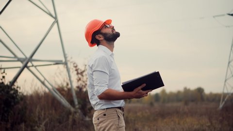 Constructor Inspect High Voltage Tower.Engineer In Hard Hat Maintenance Electricity Transmission Pylon.Electrical Engineer In Helmet Power Line.Constructor Checking High Voltage Sensor Power Line Wire