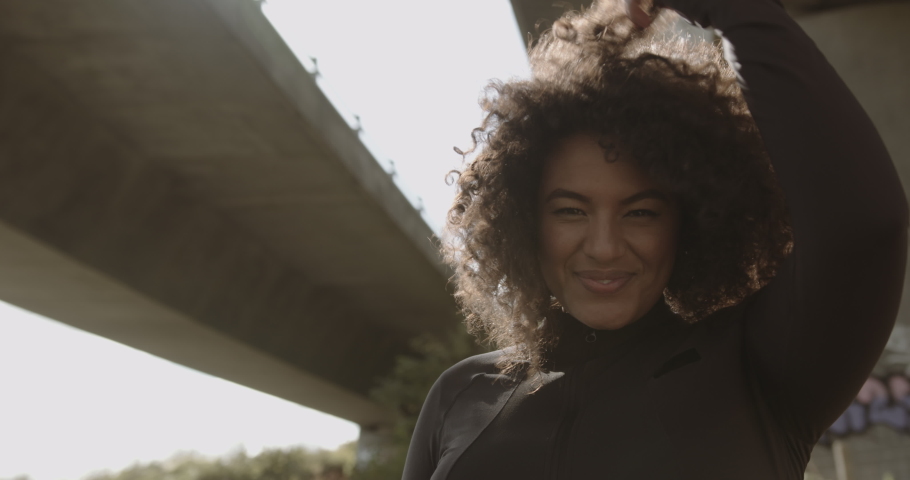 Portrait of Body positive young black female model under bridge in city, Plus size overweight Afro American woman headshot