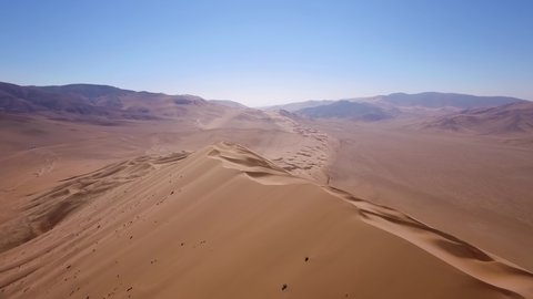 Aerial landscape shot of the golden dry sand of the Atacama desert, bright sunlight.