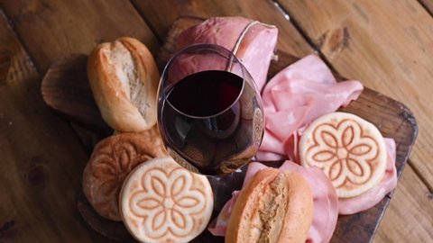 A glass of red wine, mortadela, Tigelle and different breads on a wooden table. A traditional pre-dinner starter in the northern Italian region of Emilia Romagna. footage