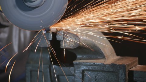 a worker cuts off metal fittings with a grinder, clamping them in a piece. The disc cuts the reinforcement first from below, then from above. Construction of metal structures. 4k