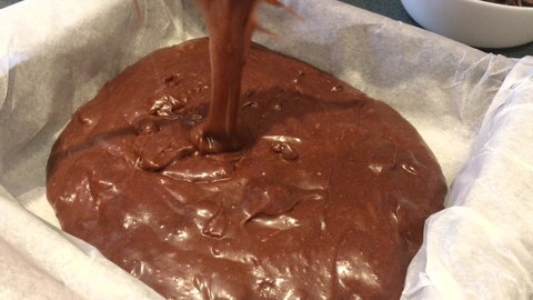 Close up, confectioner pouring dough into a mold, to make a delicious chocolate brownie, as a dessert, 4k