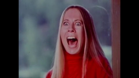 CIRCA 1973 - In this horror film, a young woman screams as an unknown being approaches, and cops drive up to the scene.