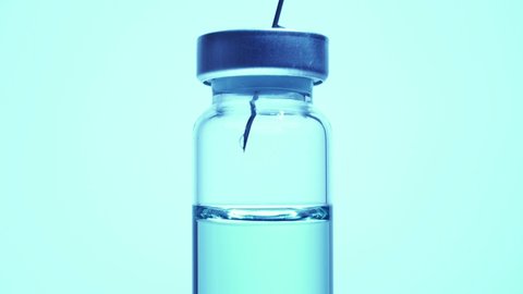 Medical vaccine scientist work in laboratory and developing research of vaccine against Coronavirus, COVID-19, MERS, 2019-ncov. Mixing blue liquid in glass vial with needle. Evaluation and trials.