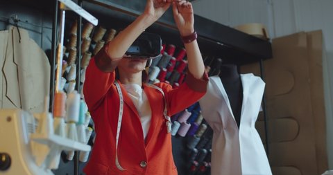 Close up portrait young Caucasian woman designer standing in own studio in VR headset Female couturier in atelier working in virtual reality glasses using futuristic innovations for fashion industry