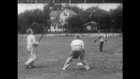 CIRCA 1950, - Adolescent boys play baseball on a playground baseball field, suburbia, a quarrel ensues but it is quickly resolved by the group.