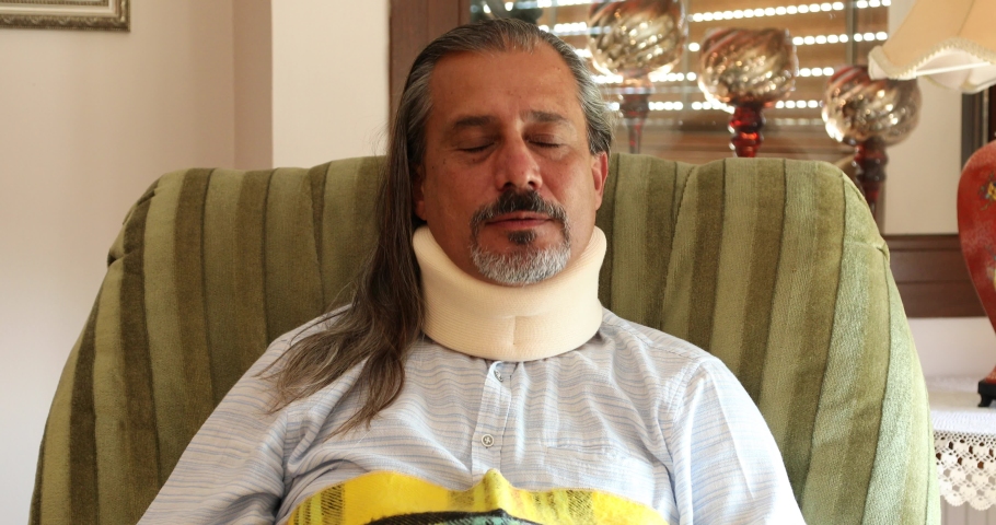 Portrait of a poor middle aged man with a neck brace sitting on sofa Royalty-Free Stock Footage #1061732143