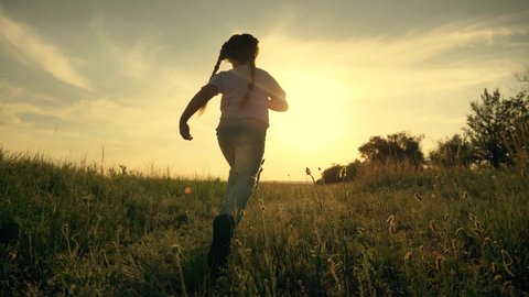 Girl is run along road. Childdream concept. Happy little girl at sunset. Kid run across field. Happy kid in field at sunset. Girl run along road at sunset. Happy family concept. Dream of child.