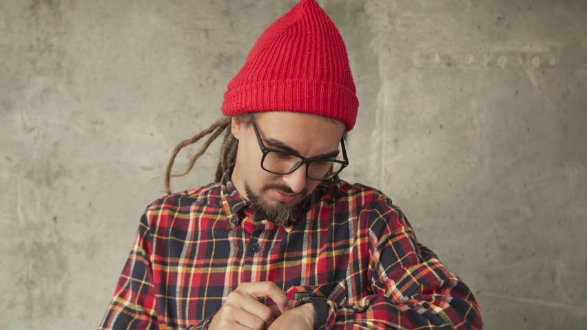 Attractive man using his smartwatch and controlling his smart home, hipster freelancer use smart watch