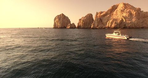 Drone footage at Cabo San Lucas Arch, Mexico, following boat cruising along water