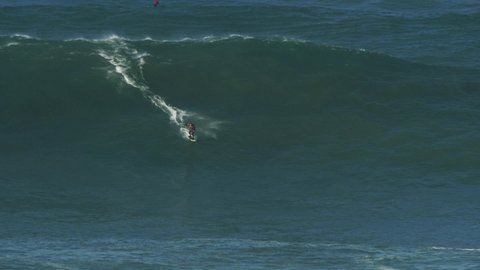 Slow motion of a big wave surfer Caio riding a monster wave in Nazaré, Portugal. Nazaré is a small village in Portugal with the biggest waves in the world.