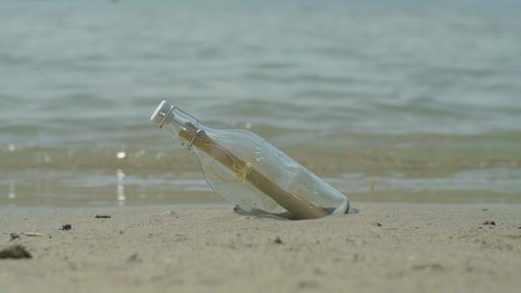 Message in the bottle from the sea, letter in the bottle on white sand beach with copy space.