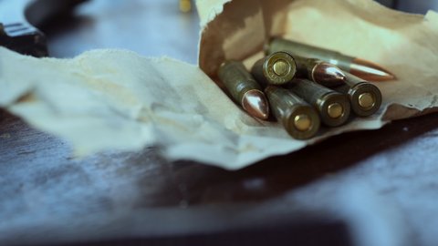 Bullets in packaging on the table. The man takes the bullets from the table. Close-up.